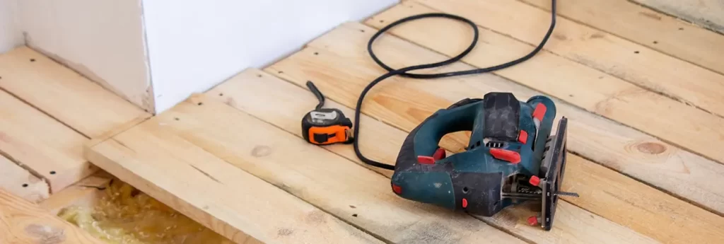 man cuts board with electric saw repair floor house selective focus